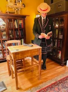 woman in green Scottish school uniform reading a book